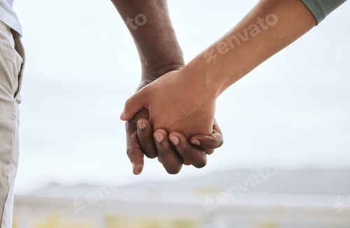 Preview: Closeup of biracial couple interlocking fingers and holding hands while bonding outdoors. Caring mi