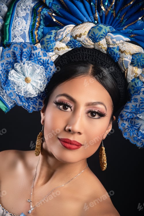 Preview: A woman wearing a blue and white headdress with gold earrings