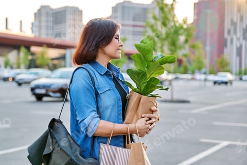 Preview: Urban portrait of middle aged woman with shopping bags in mall parking