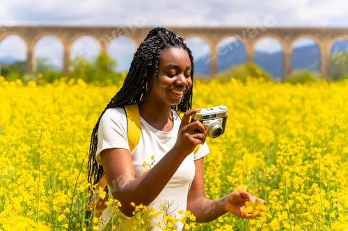 Preview: Taking photos with a vintage camera, a black ethnic girl with braids, yellow flowers
