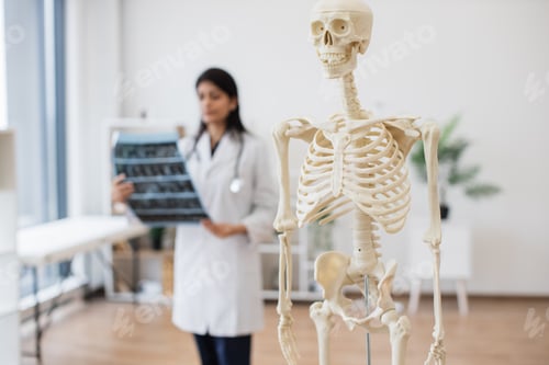 Preview: Nurse with x ray scan standing near modern of human skeleton