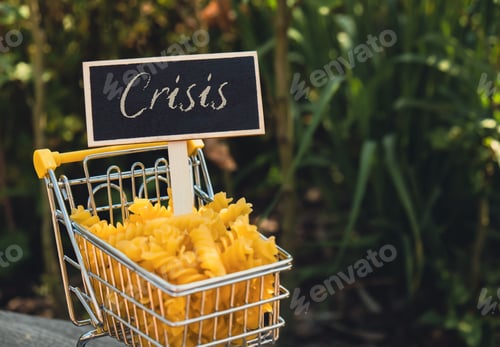 Preview: CRISIS text on Blackboard label Shopping trolley cart Filled With Pasta on agriculture background
