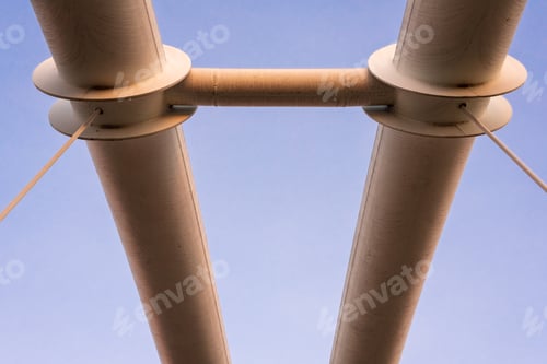 Preview: Symmetrical steel pipes supporting a suspension bridge over a river.