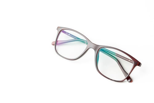 Preview: Glasses placed on a flat surface with clear lenses and colorful frames in a well-lit room