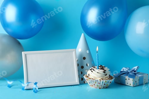 Preview: Balloons, birthday hat, cupcake, frame and gift box on blue background, space for text