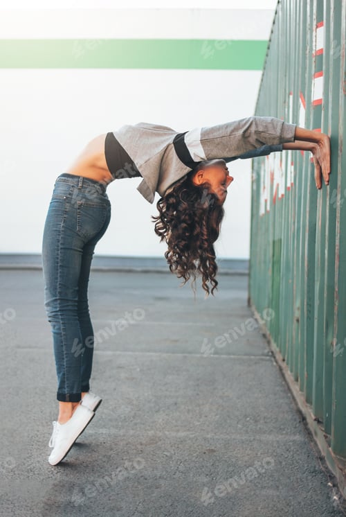 Preview: Attractive young brunette woman street dancer gymnast training outside