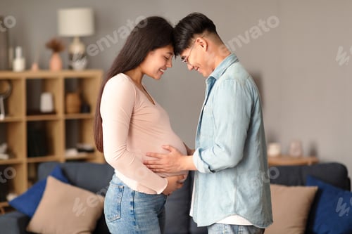 Preview: Korean couple pressing foreheads, husband touching pregnant wife belly indoors