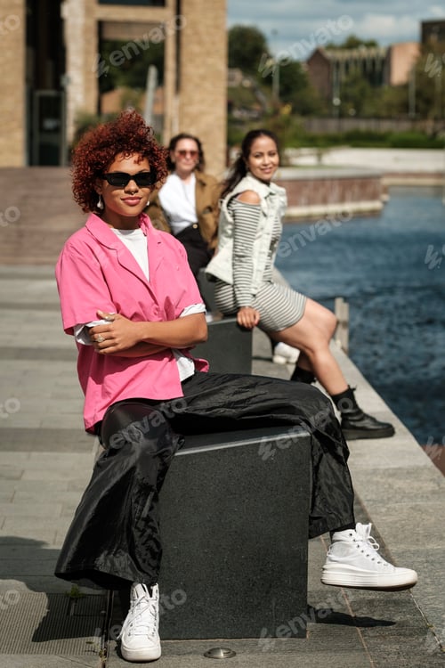 Preview: Three multiracial women sitting beside an artificial pond.