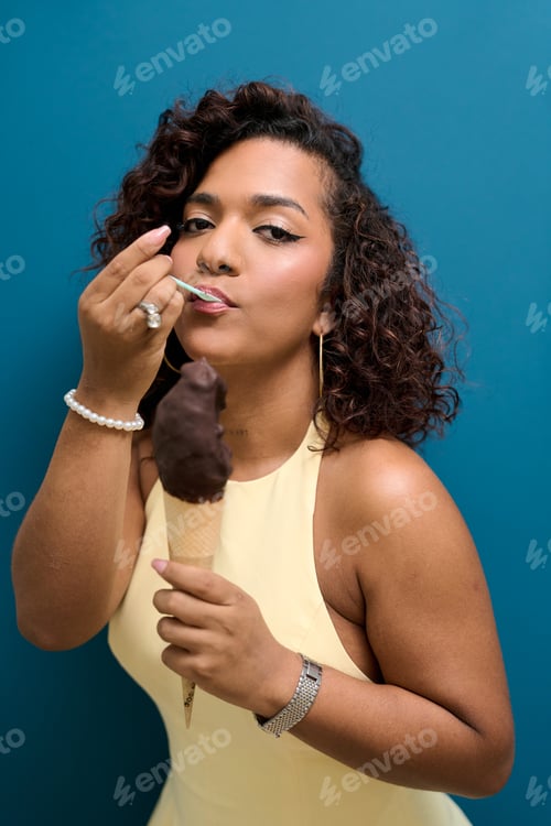 Preview: Transgender woman enjoying chocolate ice cream cone on blue background