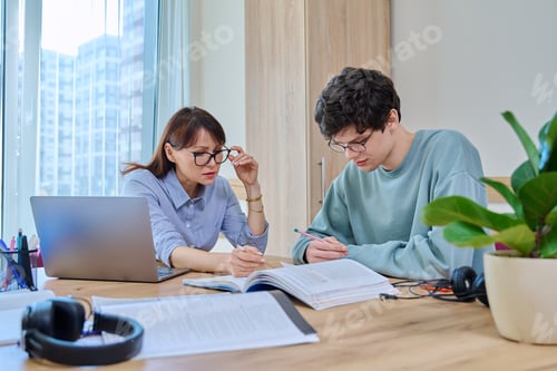 Preview: Female tutor teaching college student guy, in classroom at desk
