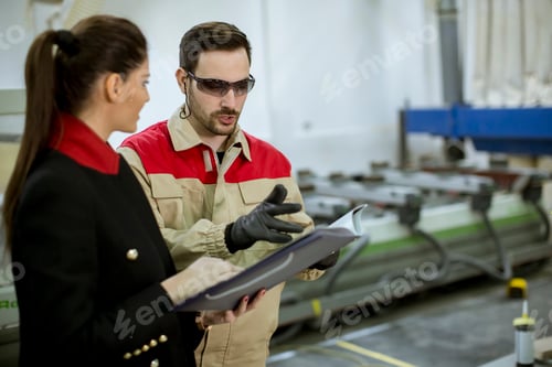 Preview: Young woman controlling process in the factory with male worker