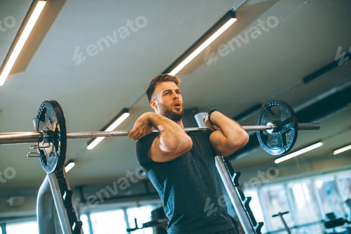 Preview: Young man working out with barbells in the gym