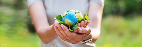 Preview: Web banner of Young woman holding small planet in hands against spring or summer green background