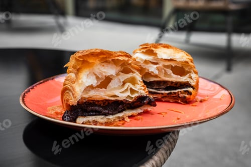 Preview: Pain au chocolat or chocolate croissant torn in half on a plate on the table