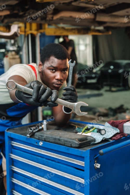 Preview: African man mechanic in uniform at the car repair station, portrait