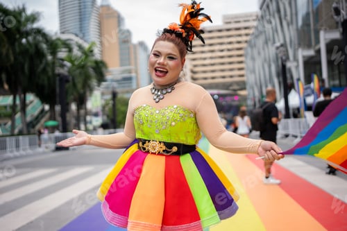 Preview: Portrait of LGBTQ woman holding rainbow flag and posing during Pride Month.