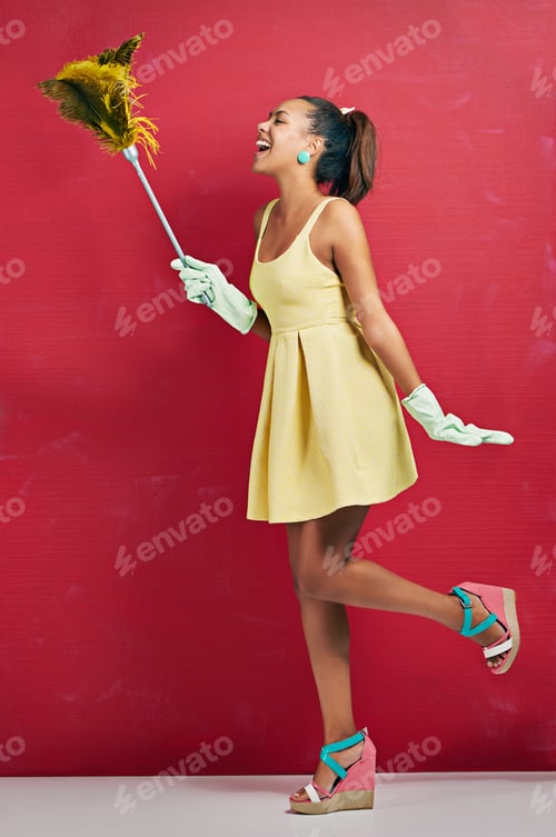 Preview: Studio shot of a young woman holding a feather duster against a red background