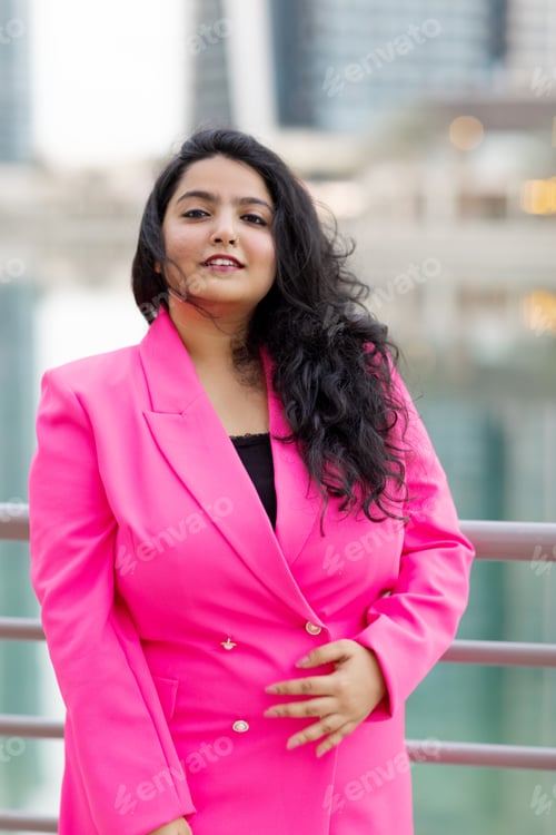 Preview: Portrait of a beautiful Indian girl in an elegant pink suit while walking along the embankment