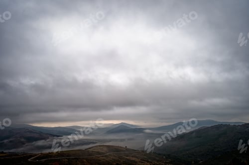 Preview: Scenic aerial view of mountains covered with fog under a cloudy sky during the daytime