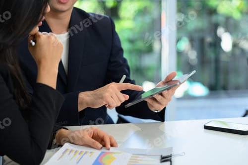 Preview: Two corporate business colleagues discussing a project and analyzing statistics on digital tablet