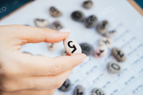 Preview: Woman numerologist hand with pebble stone with number five 5.