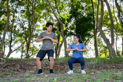Preview: Asian young couple doing morning exercise outdoors in the garden.