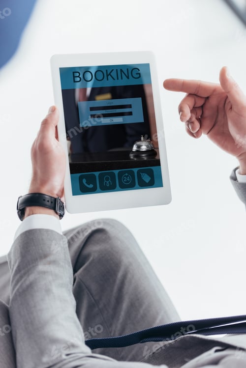 Preview: partial view of businessman using digital tablet with booking application on screen