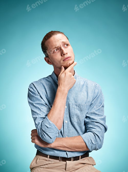 Preview: The Serious Young Man In Blue Shirt Looking At Camera Over Blue Studio Background