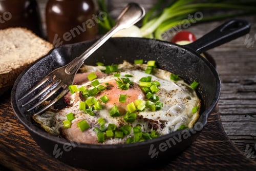 Preview: Fried eggs with ham on an old wooden background.