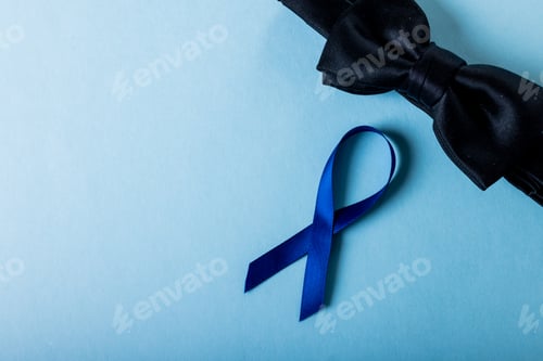 Preview: Directly above shot of blue prostate cancer awareness ribbon with black bowtie over blue background