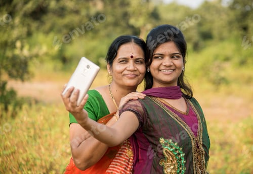 Preview: Mother and daughter taking a selfie with a smartphone in park.