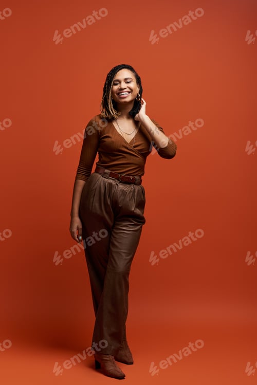 Preview: Confident young African American woman with braids posing in a vibrant studio