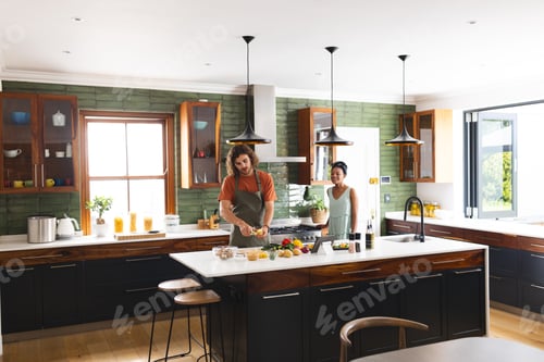 Preview: A diverse couple is preparing meal together in a modern kitchen with copy space