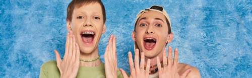 Preview: Astonished homosexual friends with open mouth looking at camera while celebrating lgbt community