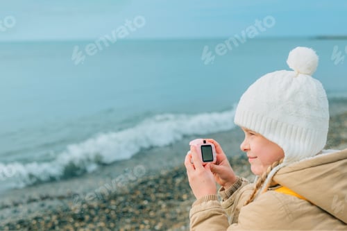 Preview: a little girl squinting photographs the autumn, spring seascape on a childrens pink camera. Hobby