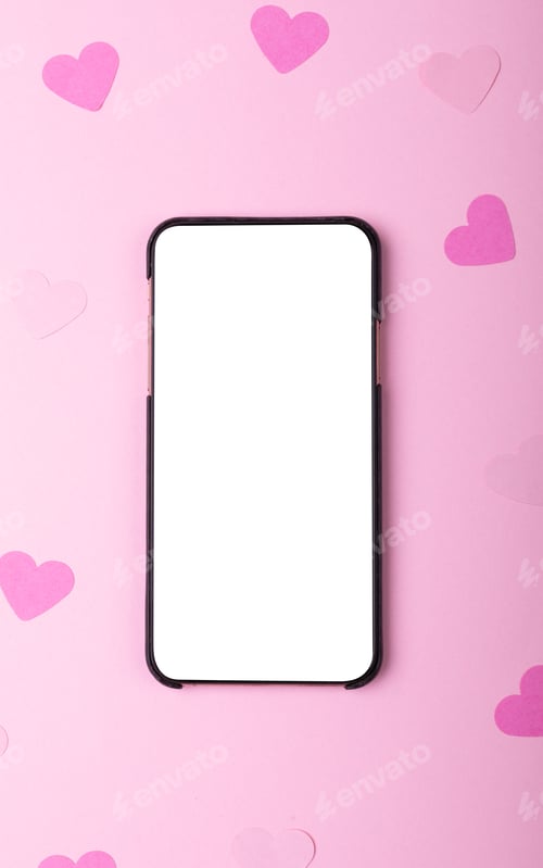 Preview: Directly above shot of smart phone with copy space and heart shaped papers on pink background