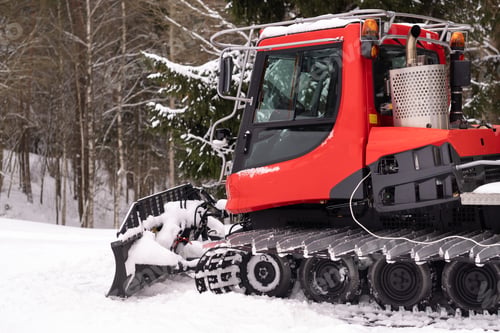 Preview: A snowplow on red tracks standing in winter in the forest near the barn