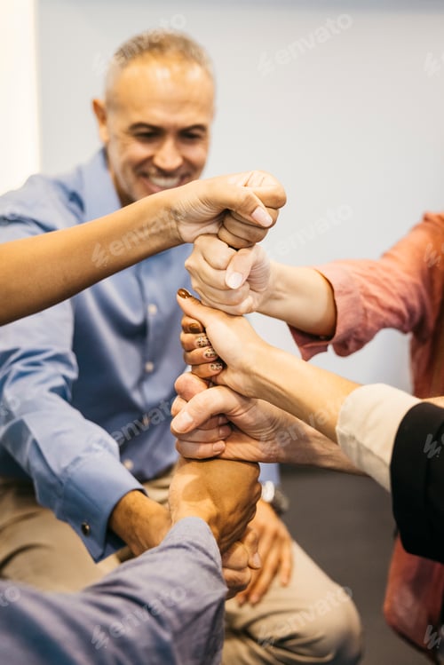 Preview: Business team stacking fists demonstrating unity and collaboration