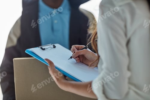 Preview: Cropped shot of a businesswoman signing for a package delivered by a courier to her office