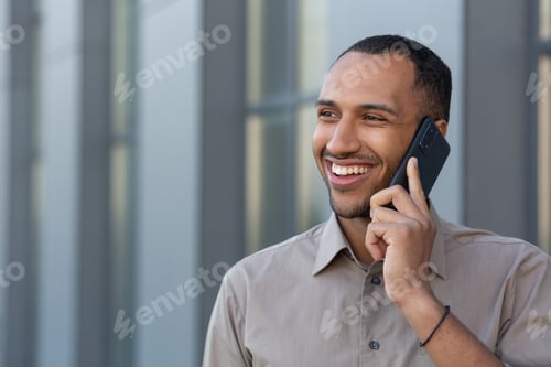 Preview: Cheerful and smiling African American office worker talking on the phone, man outside office