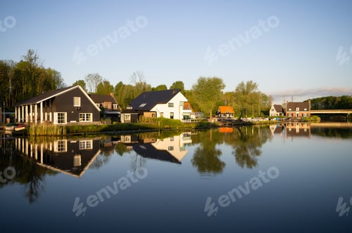 Preview: Beautiful shot of the water reflecting the houses on the shore under a blue sky
