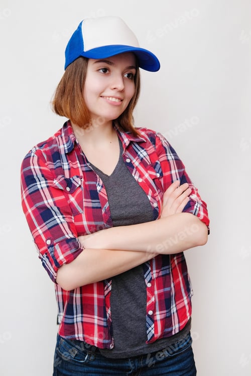 Preview: Hipster In A Plaid Shirt And A Cap. Young Woman On White Background.