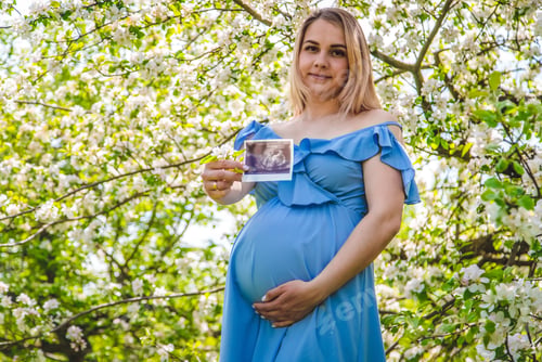 Preview: Pregnant woman in the garden of flowering apple trees ultrasound. Selective focus.