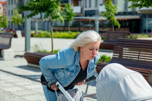 Vorschau: ukrainische Großmutter mit Enkelin im Kinderwagen geht die Straße entlang