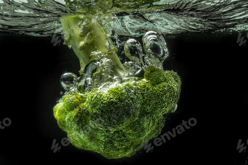 Preview: Green broccoli falling in water with splash on black with air bubbles