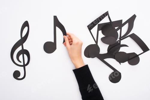 Preview: Cropped view of female hand with paper cut black music notes on white background