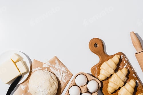 Preview: Fresh Croissants on Wooden Cutting Board Near Raw Dough, Knife, Rolling Pin, Butter And Eggs