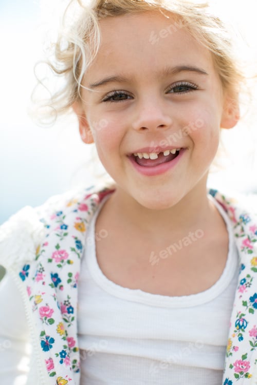 Preview: Portrait of cute blond girl with tooth missing at coast
