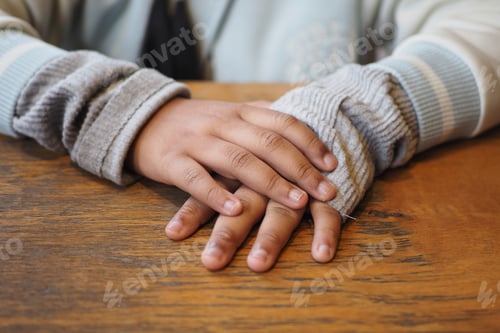 Preview: Child hands resting on wooden table during quiet time