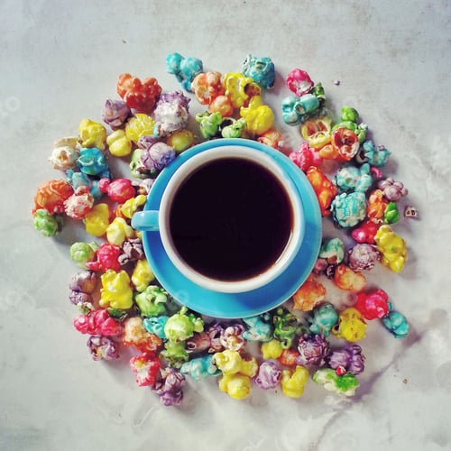 Preview: cup of coffee with colourful popcorn candy on table top